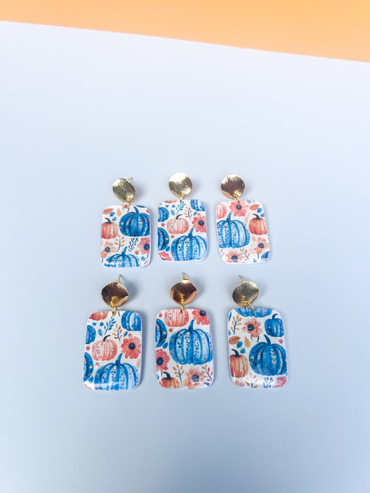 Set of floral and pumpkin patterned earrings on a blue and orange background