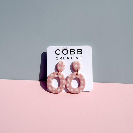 Pair of pink gingham earrings on a COBB Creative branded card against a gray background