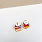 Stacked colorful book earrings on a white surface with a beige background