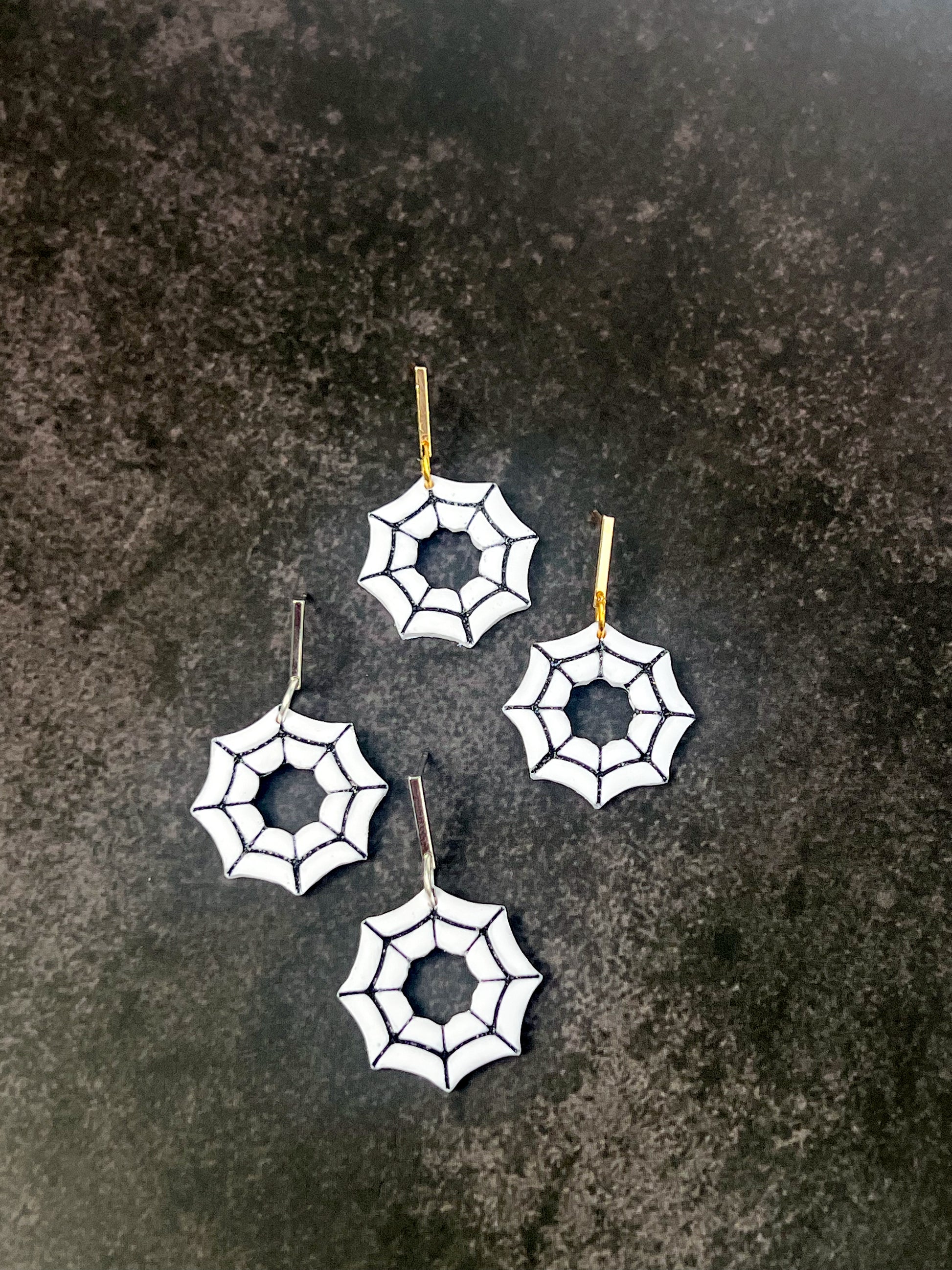 Spider web earrings on a dark textured surface