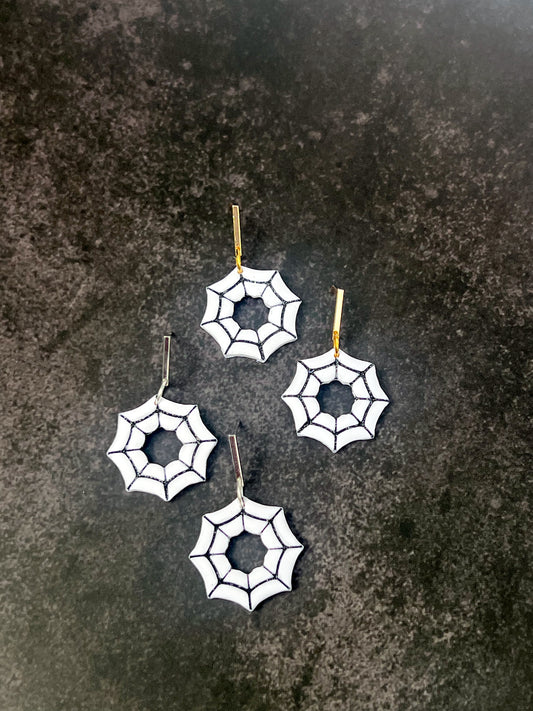 Spider web earrings on a dark textured surface