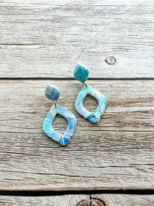 Blue and green marbled earrings on a wooden surface