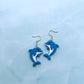 Blue dolphin-shaped earrings on a light blue background