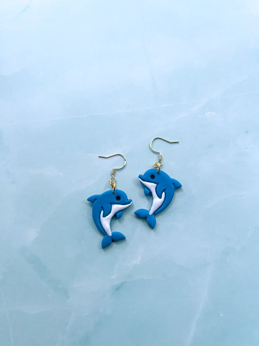 Blue dolphin-shaped earrings on a light blue background