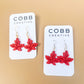 Red leaf-shaped earrings on Cobb Creative branded cards against a beige background.